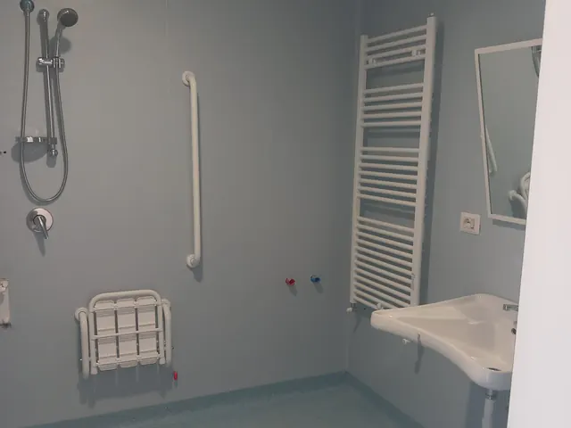 Bagno accessibile con doccia e pavimento in PVC azzurro
