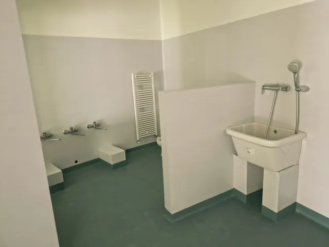Bagno d’asilo con lavatoio e pavimento in linoleum verde acqua