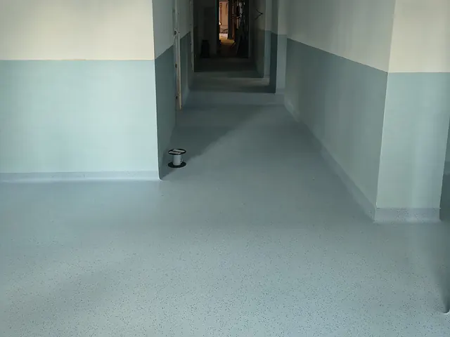 Corridoio con pavimento in PVC azzurro e pareti rivestite a metà