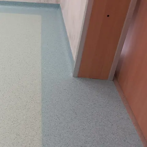 Locale con pavimento in PVC granigliato chiaro e bordo verde acqua