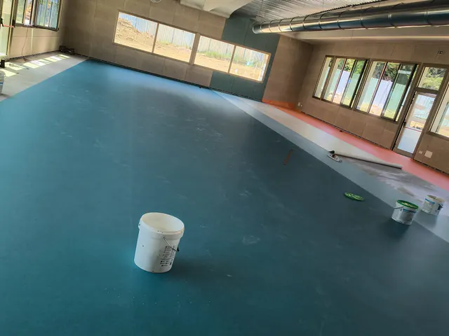 Grande sala con pavimento in PVC blu petrolio durante la posa