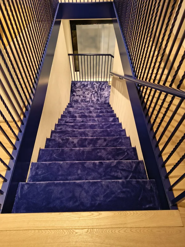 Scala con ringhiere nere e gradini in moquette blu