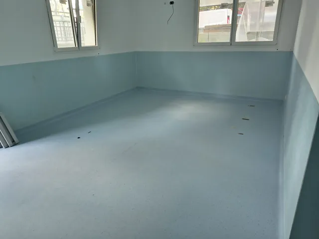Stanza con pavimento in PVC azzurro e pareti rivestite a metà